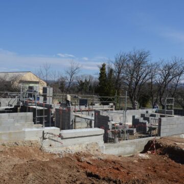 Outdoor construction site showing cinder block walls and scaffolding under a clear sky.